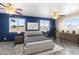 Spacious bedroom with ceiling fan, windows, and stylish blue accent wall with neutral furniture at 9163 W Swansea Dr, Arizona City, AZ 85123