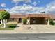 Charming single-story home with a carport and well-maintained desert landscaping under a partly cloudy sky at 9746 N 105Th Dr, Sun City, AZ 85351