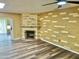 Living room featuring a fireplace, decorative wall, ceiling fan, and updated hard wood flooring at 9746 N 105Th Dr, Sun City, AZ 85351