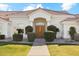 Close up on the front of a charming single-story home with lush lawn, mature landscaping, and double wooden doors at 1743 E Menlo St, Mesa, AZ 85203