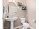 Clean bathroom with pedestal sink, toilet, and decorative shelving at 17774 W Watson Ln, Surprise, AZ 85388