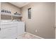 Bright laundry room features washer, dryer, and shelving at 17774 W Watson Ln, Surprise, AZ 85388