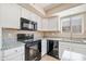 Kitchen with white cabinets, granite counters, and black appliances at 1799 E Erie St, Gilbert, AZ 85295