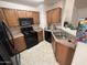 Kitchen with wood cabinets, black appliances, and double sink at 19379 N Miller Way, Maricopa, AZ 85139