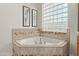 Spa-like bathroom with corner bathtub, tile surround, and a large block window at 32032 N 52Nd Way, Cave Creek, AZ 85331