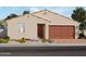 One-story home with tan exterior, brown garage door, and landscaping at 4232 W Hannah St, San Tan Valley, AZ 85144