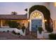 Front view of home with arched entryway and lush landscaping at 7348 N Red Ledge Dr, Paradise Valley, AZ 85253