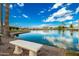 Serene lake view with a stone bench and lush landscaping at 10428 E Hercules Dr, Sun Lakes, AZ 85248