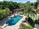 An aerial view captures a gorgeous pool and spa area surrounded by lush landscaping and outdoor seating at 11571 E Cochise Dr, Scottsdale, AZ 85259
