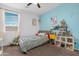 Cozy bedroom featuring a blue accent wall, playful decorations, a ceiling fan, and a window with blinds at 22501 E Indiana Ave, Queen Creek, AZ 85142