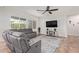 Bright living room with gray sectional sofa, large TV, and tile flooring at 24147 N 165Th Ln, Surprise, AZ 85387
