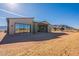 Rear view of a modern, tan house with large windows and a covered patio at 25572 N 119Th St, Scottsdale, AZ 85255