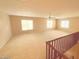 Open loft area with neutral carpet, multiple windows, and staircase at 43439 W Magnolia Rd, Maricopa, AZ 85138