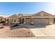 Tan two-story house with a three-car garage and desert landscaping at 15491 W Amelia Dr, Goodyear, AZ 85395