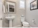 Well-lit powder room with a pedestal sink, decorative mirror, and a framed art print on the wall at 1921 E Lantana Dr, Chandler, AZ 85286