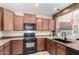 Kitchen with dark wood cabinets, granite countertops, and black appliances at 25823 N 122Nd Ln, Peoria, AZ 85383