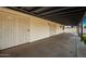 Covered back patio featuring access doors, concrete floor, and overhead lighting, ideal for outdoor relaxation and entertaining at 3250 W Mercer N Ln, Phoenix, AZ 85029