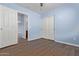 Bedroom with light blue walls, wood-look floors, and double door closet at 36532 W Barcelona Ln, Maricopa, AZ 85138