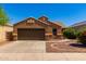 Single-story house with brown exterior, two-car garage, and landscaped front yard at 36532 W Barcelona Ln, Maricopa, AZ 85138