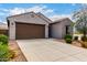 Beautiful home with a brown garage door, lush bushes, and desert landscaping, offering great curb appeal at 5013 S 112Th Ave, Tolleson, AZ 85353