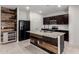 Stylish kitchen with dark cabinets, a granite island with a sink, and a modern backsplash at 5013 S 112Th Ave, Tolleson, AZ 85353