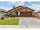 Tan house with brown garage door, well-maintained lawn, and shrubs at 10245 W Jessie Ln, Peoria, AZ 85383