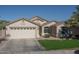 Tan two-car garage home with a neatly landscaped lawn at 11246 W Chase Dr, Avondale, AZ 85323