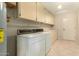 Functional laundry room with washer, dryer, and overhead cabinets at 12923 W Ballad Dr, Sun City West, AZ 85375