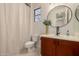 Clean bathroom with wood cabinets, a toilet, and a large round mirror at 2128 E Leo Pl, Chandler, AZ 85249