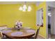 Sunny dining area featuring a round wooden table with purple placemats and a modern chandelier at 2172 W Pinkley Ave, Coolidge, AZ 85128