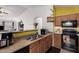 Open kitchen area with wooden cabinets, stainless steel sink, black appliances, and a breakfast bar at 2172 W Pinkley Ave, Coolidge, AZ 85128