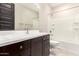 Modern bathroom with dark vanity, white tub, and tile flooring at 11667 W Marguerite Ave, Avondale, AZ 85323