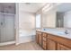 Bathroom features a glass shower, soaking tub, dual sink vanity and tile floors at 15144 W Washington St, Goodyear, AZ 85338