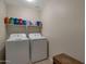 Functional laundry room equipped with a washer, dryer, and storage shelving at 15144 W Washington St, Goodyear, AZ 85338