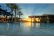 Inviting pool with palm trees, pergolas, and clear water under a bright sunset at 210 E Bergamot Ln, Queen Creek, AZ 85140
