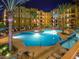 Night view of resort-style pool with palm trees and lounge chairs at 5450 E Deer Valley Dr # 1004, Phoenix, AZ 85054