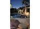 Night view of a kidney shaped pool with a pergola and palm trees at 7421 W Villa Hermosa Ave, Glendale, AZ 85310