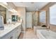 Elegant bathroom with double vanities, a soaking tub, and a walk-in shower at 15813 N 109Th Ln, Sun City, AZ 85351