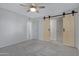 Spacious bedroom featuring modern barn doors, a ceiling fan and neutral carpeting at 17242 N 16Th Dr # 9, Phoenix, AZ 85023