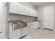 Bright laundry room, featuring a farmhouse sink, white cabinets, and wood-look tile floors at 17330 W Royal Palm Rd, Waddell, AZ 85355