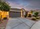 One-story home with gray garage door, landscaping, and a welcoming front porch at 18280 N Piccolo Dr, Maricopa, AZ 85138