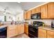 Kitchen with light wood cabinets, black appliances, and tiled floors at 25875 W St Catherine Ave, Buckeye, AZ 85326