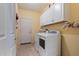 Bright laundry room with washer, dryer, and upper cabinets at 25940 W Oraibi Dr, Buckeye, AZ 85396