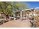 Outdoor patio with pergola, table, chairs, and lush landscaping at 28821 N Ashbrook Ln, Queen Creek, AZ 85144