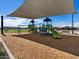 Community playground area with swings, slides, and other play structures, shaded from the sun at 3201 E Hayden Rose Ave, San Tan Valley, AZ 85143