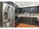 Modern kitchen with dark cabinetry, stainless steel appliances, and terracotta tile floors at 7258 E Manzanita Dr, Scottsdale, AZ 85258