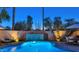 Blue illuminated pool at dusk with patio seating at 7258 E Manzanita Dr, Scottsdale, AZ 85258