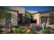 Desert home's front entrance with modern door and xeriscaped yard featuring colorful native plants at 11972 E Yearling Rd # 20, Scottsdale, AZ 85255