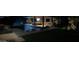 Night view of inground pool with poolside loungers, outdoor kitchen, and lush landscaping at 11972 E Yearling Rd # 20, Scottsdale, AZ 85255
