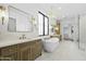 Luxurious bathroom featuring dual vanities, a soaking tub, elegant lighting, and a glass-enclosed shower at 19912 E Karsten Dr, Queen Creek, AZ 85142